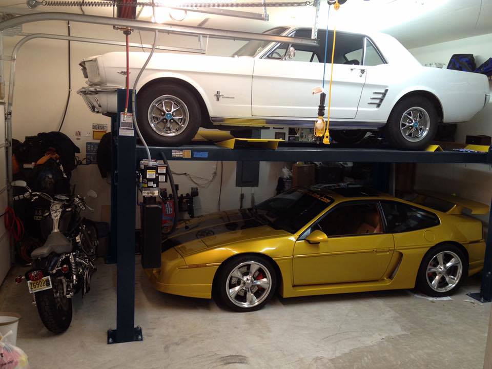 Yellow car under and white car over on Gunmetal Gray BendPak four-post car lift