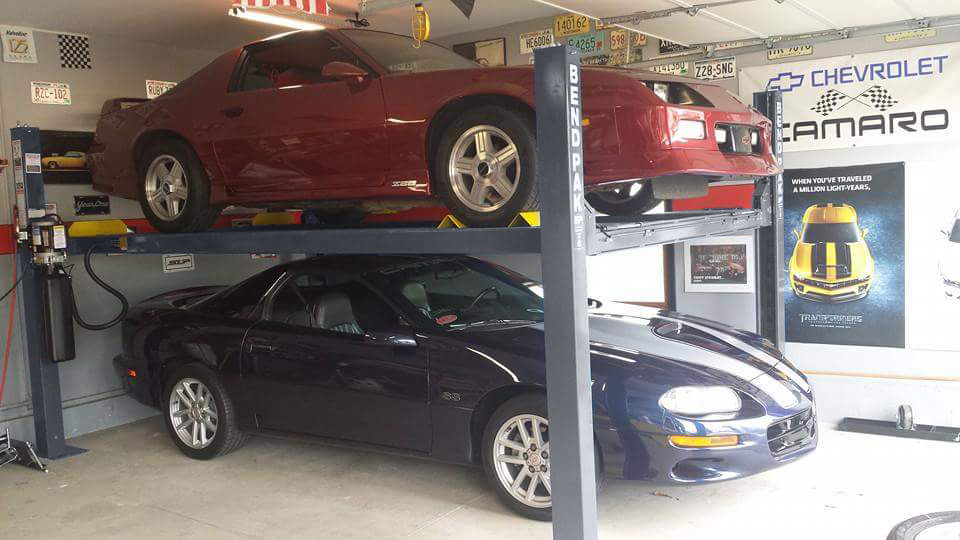 Blue Chevy Camaro under and red Chevy Camaro over on Gunmetal Gray BendPak four-post car lift