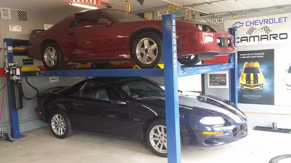 Blue Chevy Camaro under and red Chevy Camaro over on blue BendPak four-post car lift